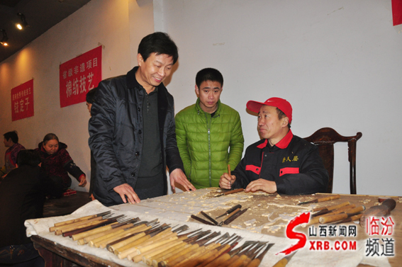 03、臨汾市非物質(zhì)文化遺產(chǎn)主任任江波（左一）在向制作師傅了解晉作家具制作雕刻技藝